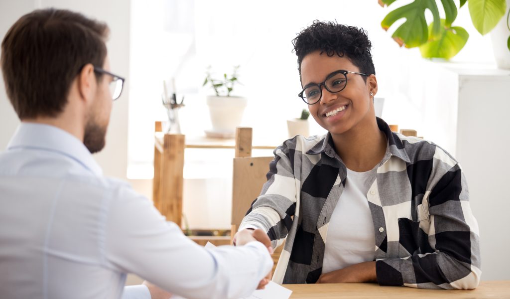 Happy confident african applicant shaking hand of hr manager offer new job, black candidate getting hired at job interview, handshake client at meeting, making good first impression employment concept
